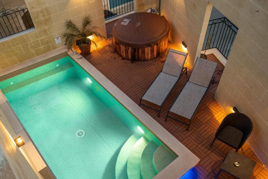 Tal-BarmilNarcisa - Luxury 3BR Traditional House with Pool, Cinema & Hot Tub的游泳池的顶部景色,设有椅子和桶
