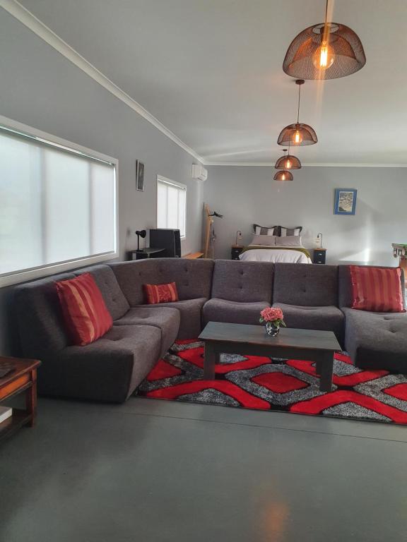 玛塔玛塔The Red Shed的客厅配有灰色沙发和红色枕头