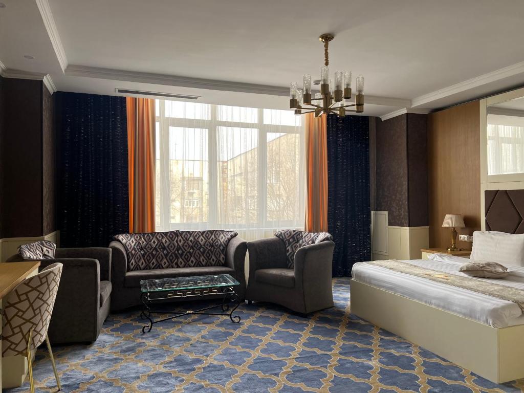阿拉木图阿拉木图大埃尔比勒酒店的一间卧室配有一张床、一张沙发和椅子