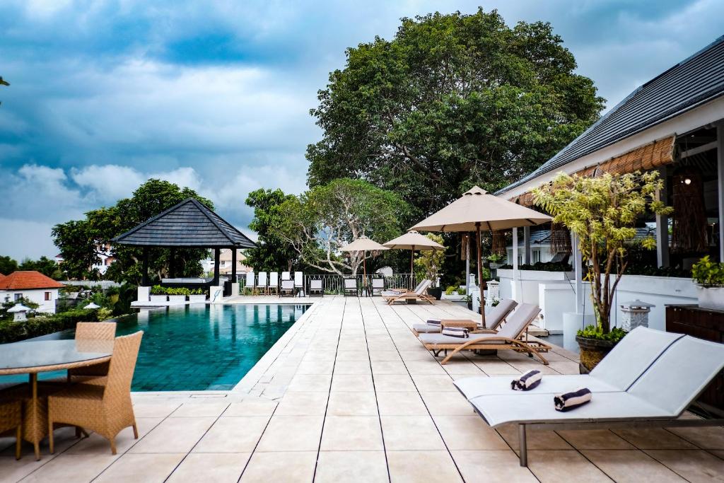 乌鲁瓦图Villa Puri Balangan的度假村的游泳池,配有椅子和遮阳伞