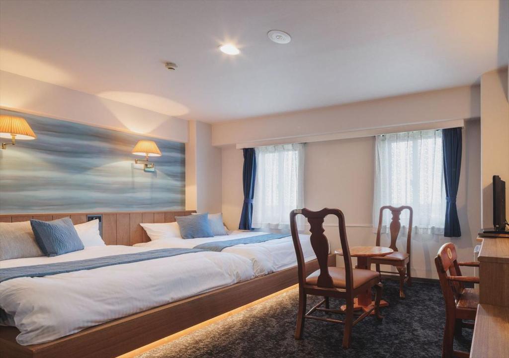 宫古岛Miyako Daiichi Hotel的酒店客房带两张床和一张桌子以及椅子。