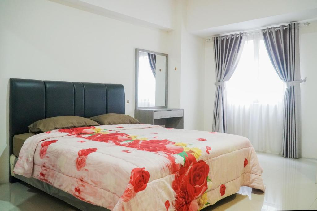 KemplangBandara City Apartment Near Bandara Soekarno Hatta - Type Studio的一间卧室配有一张带花卉毯子的床