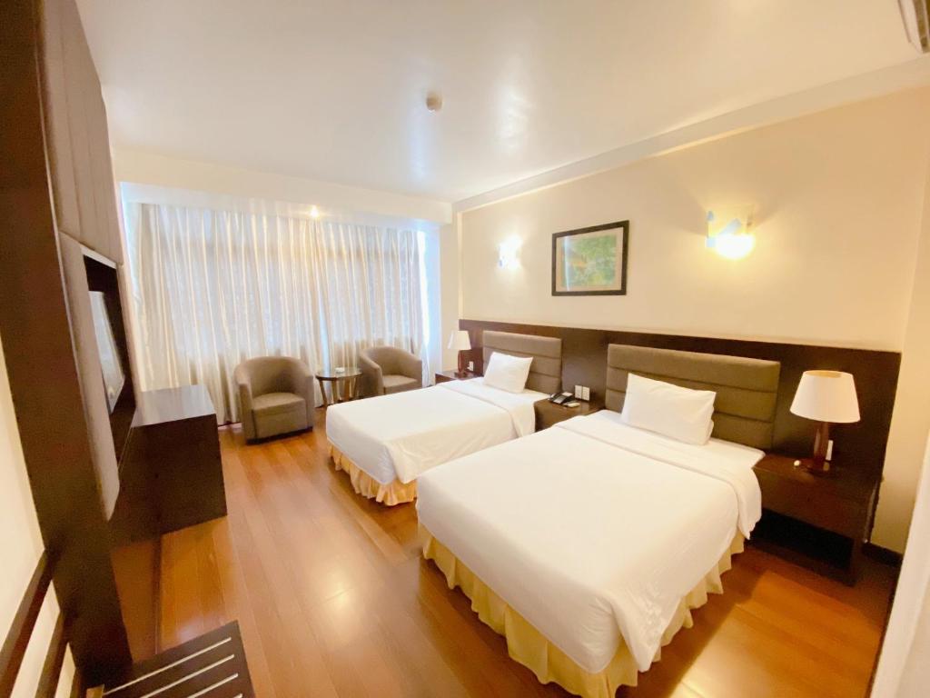 荣市Muong Thanh Thanh Nien Vinh的酒店客房,配有两张床和椅子