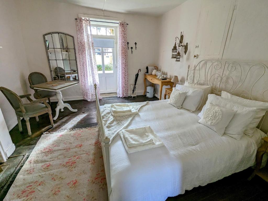Jumilhac-le-GrandSous le Chateau的卧室配有白色的床、桌子和窗户。