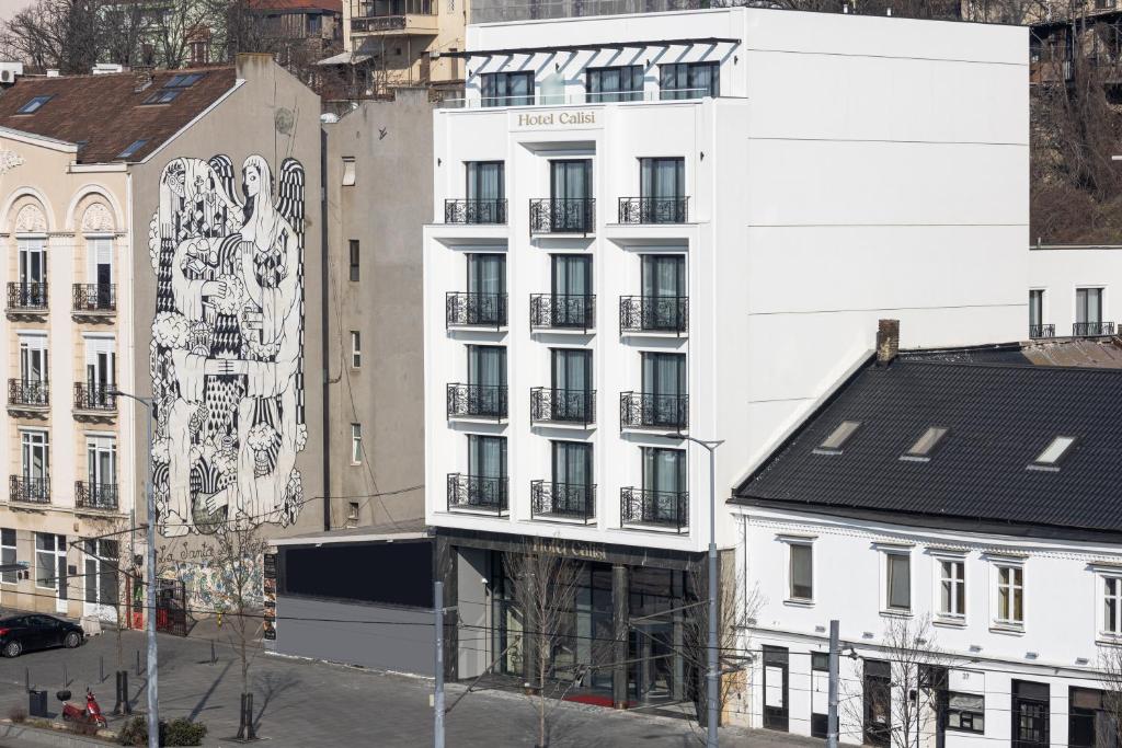 贝尔格莱德Calisi Hotel的白色的建筑,旁边是壁画