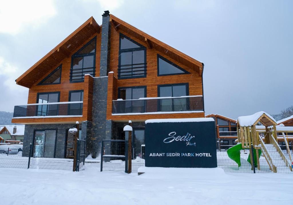 博卢Abant Sedir Park Butik Otel的雪地中的一座建筑,带有游乐场