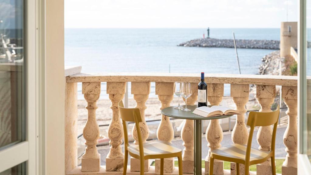 圣温琴佐Suite vista mare的阳台配有桌椅和一瓶葡萄酒。