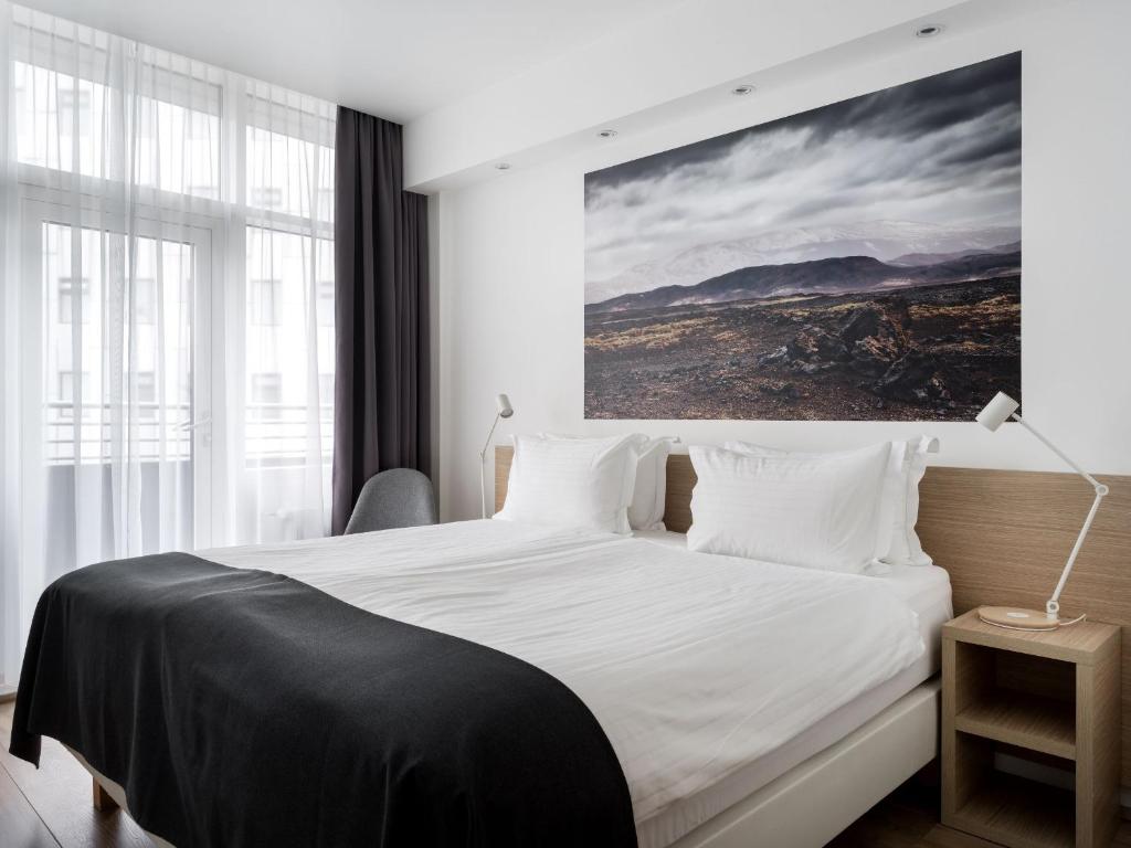 雷克雅未克凯亚风暴酒店的卧室配有一张白色床,墙上挂有绘画作品