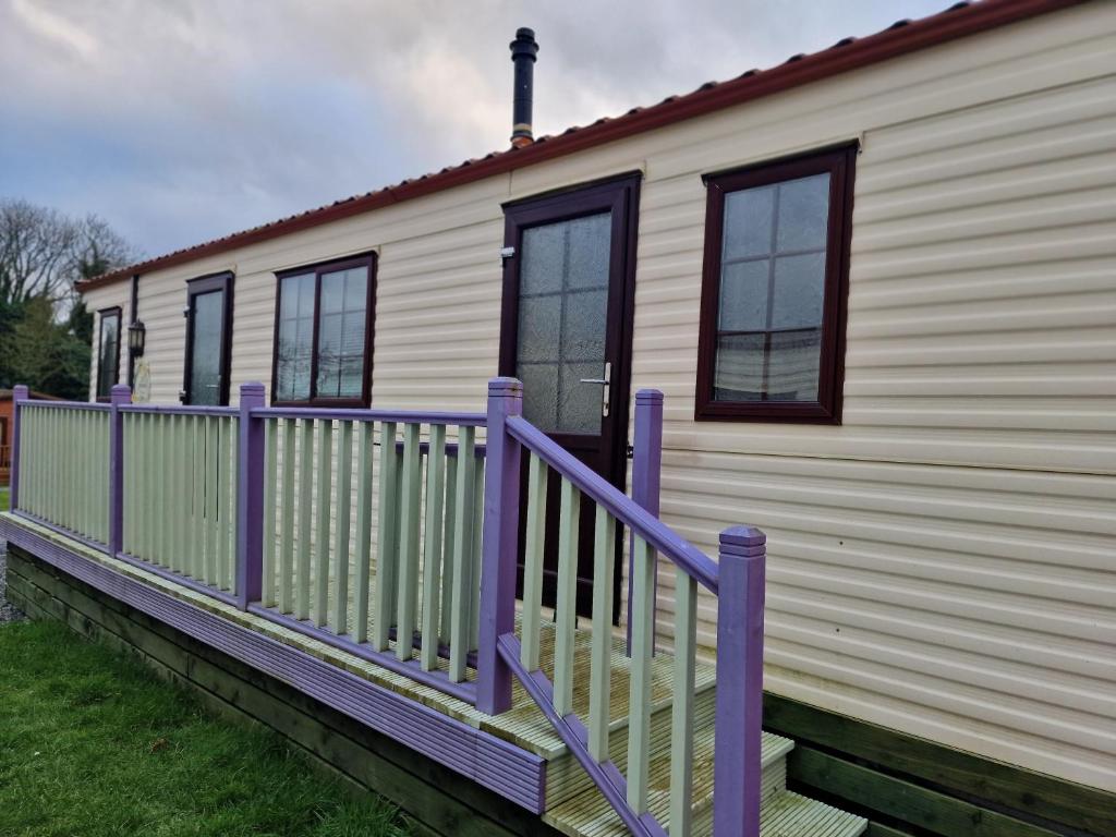 牛顿斯图尔特Castlewigg holiday park Whithorn 2 bed caravan的移动房屋设有紫色门廊和窗户