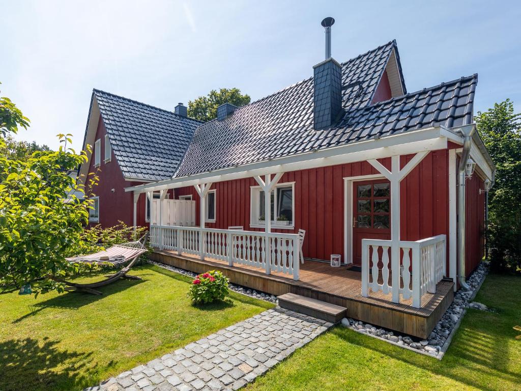 青斯特Ferienwohnung Ostseestrand Zingst的一座红色的房子,设有甲板和庭院