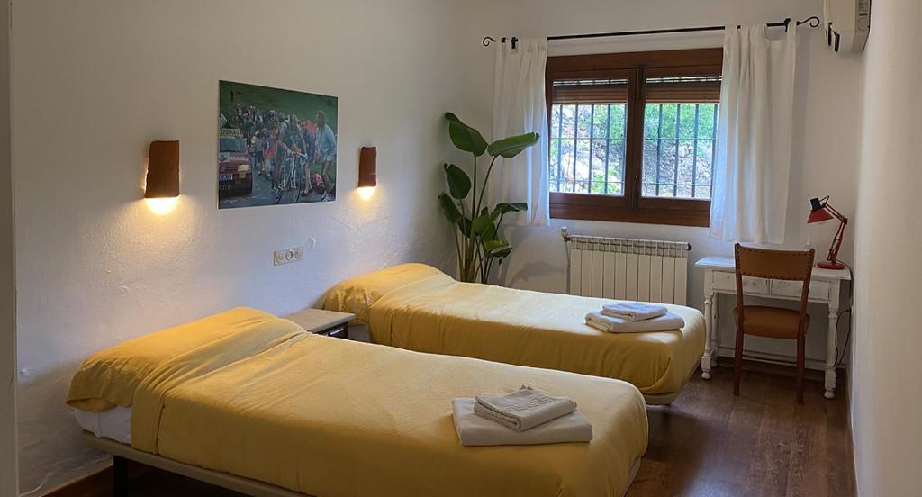 GualchosLa Ventera - summer hotel的客房设有两张床、一张桌子和一扇窗户。