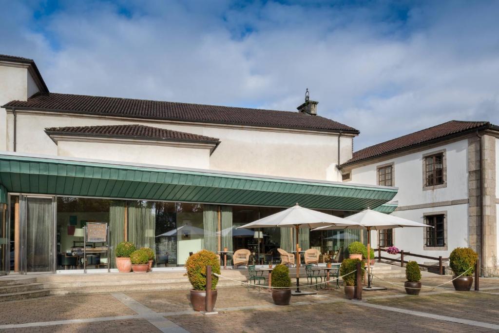 圣地亚哥－德孔波斯特拉卡门宫傲途格精选酒店的前面有桌子和伞的建筑
