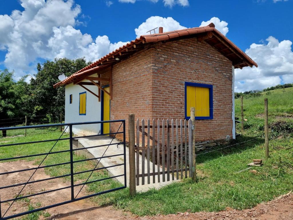卡兰卡斯Chalé Boa Vista的一间黄色门和栅栏的小砖房子