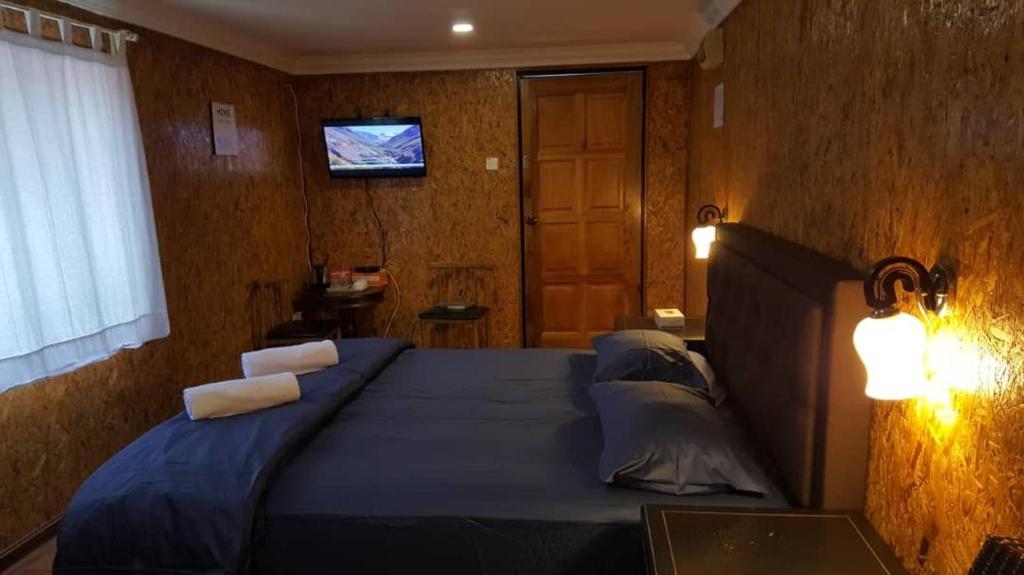 MerlimauHomestay Umbai Kelana的一间卧室配有一张蓝色的床、枕头和电视