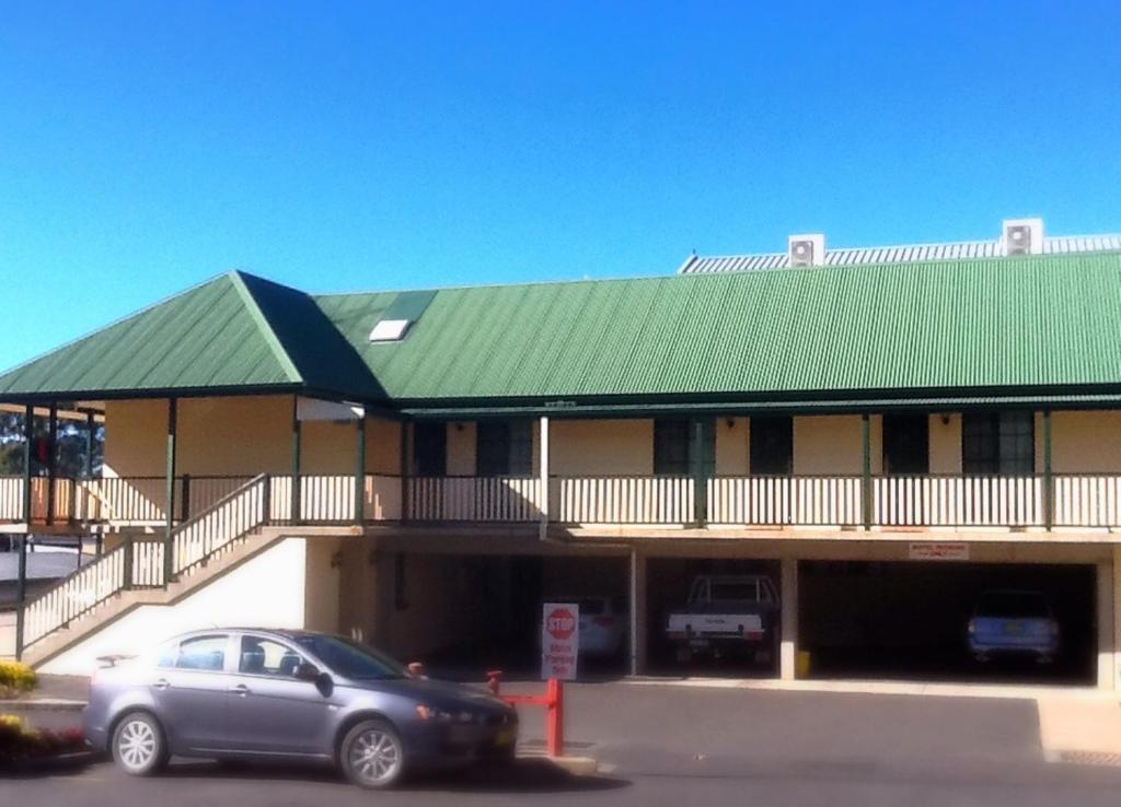 奥兰治Town Square Motel的停在有绿色屋顶的建筑前面的汽车