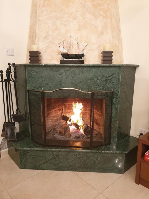 卡科佩特里亚Kakopetria's Holiday House的绿色壁炉,壁炉里放着火