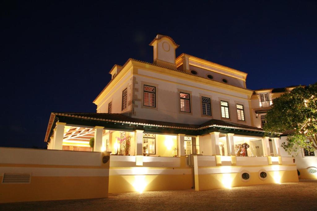 古勒冈卢西塔诺酒店的一座白色的大建筑,晚上有灯