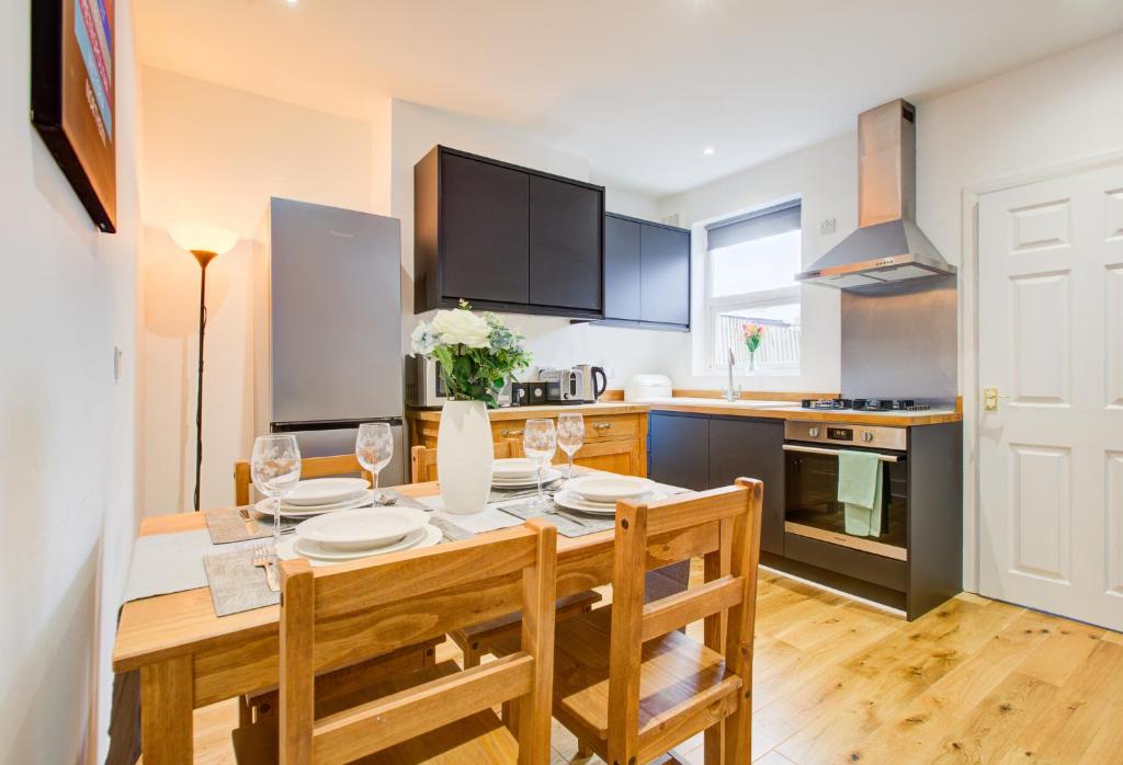 伦敦Statera Apartments - 2-Bed House in Stratford的一间带木桌和椅子的厨房以及一间用餐室