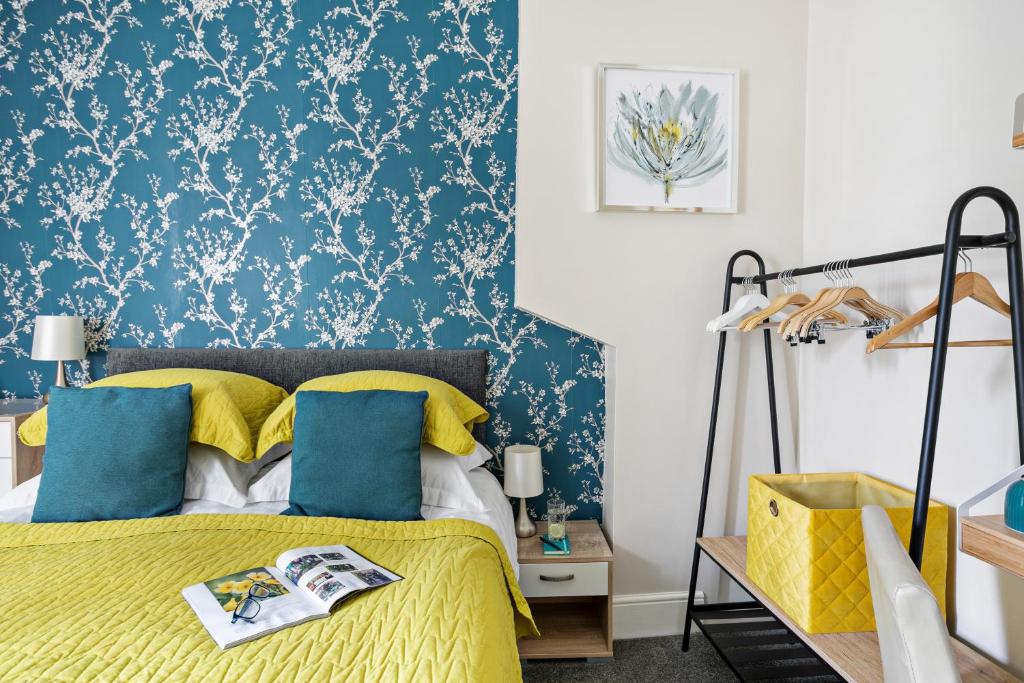 佩恩顿舍伍德旅馆的一间卧室配有黄色的床,拥有蓝色和白色的壁纸