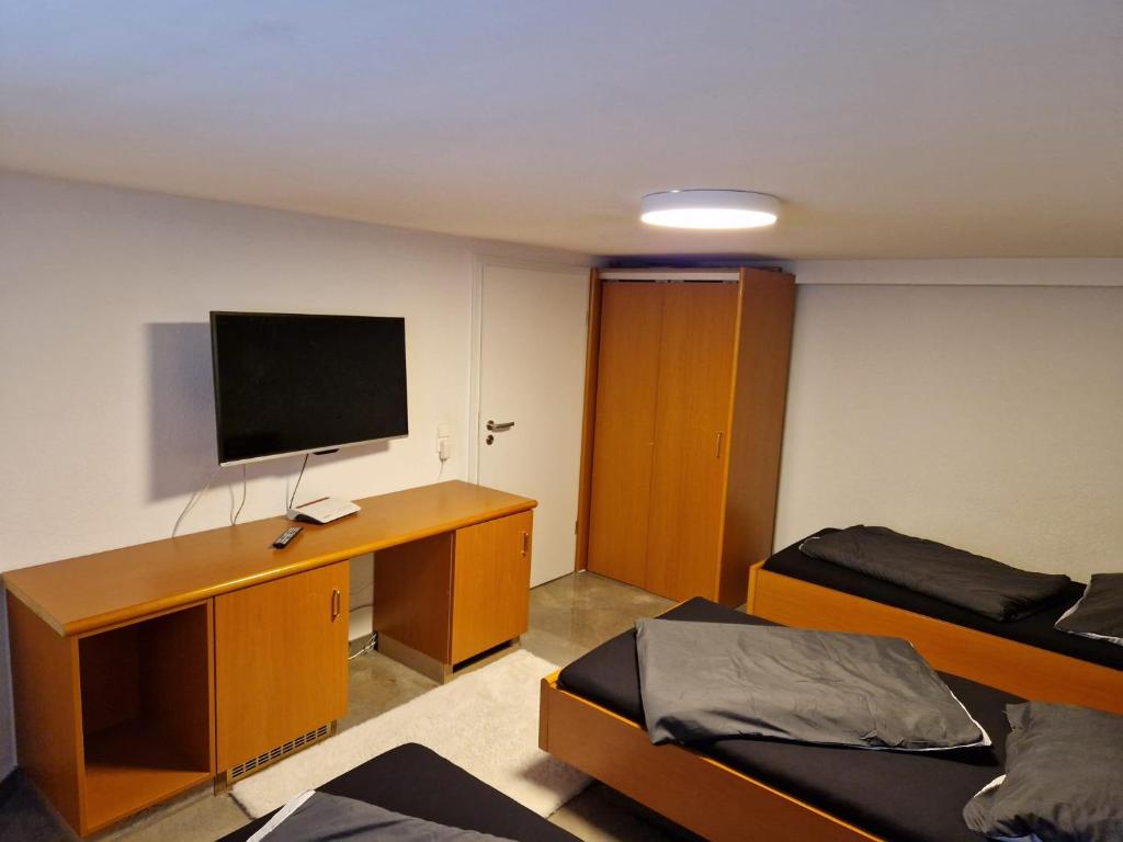 穆更斯托姆Monteurzimmer-mit GemeinschaftsBad und Küche BEI RASTATT的客房设有两张床和一张书桌及一台电视。