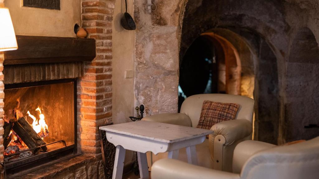 Horche卡萨乡村安德里亚酒店的壁炉前配有两把椅子和一张桌子