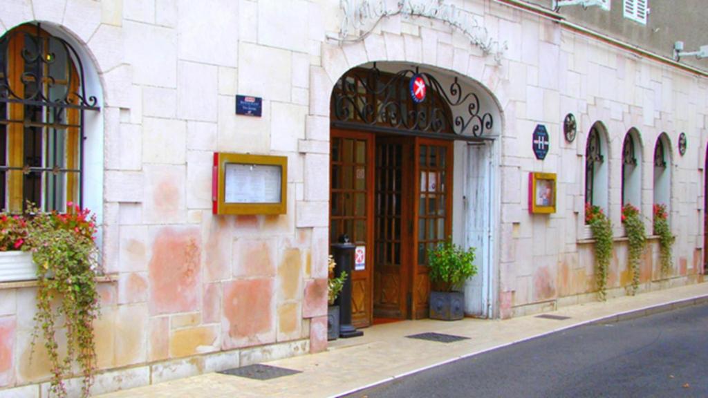 帕雷·勒·毛尼尔The Originals Boutique, Hostellerie des Trois Pigeons, Paray-le-Monial (Inter-Hotel)的街道上一座石头建筑,设有大木门
