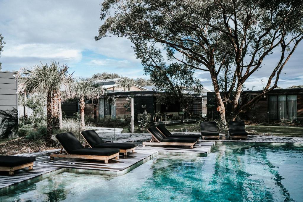Shoalhaven HeadsBangalay Luxury Villas的一座房子旁带躺椅的游泳池