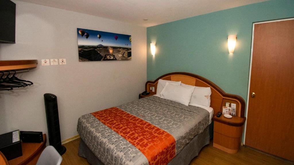 墨西哥城Hotel El Conde Naucalpan Only Adults的一间卧室配有一张带橙色和灰色毯子的床