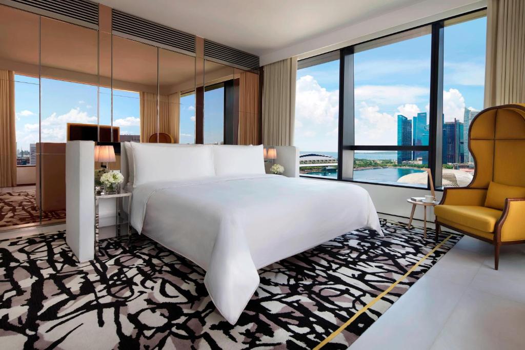 新加坡JW Marriott Hotel Singapore South Beach的卧室配有一张白色大床和一把椅子