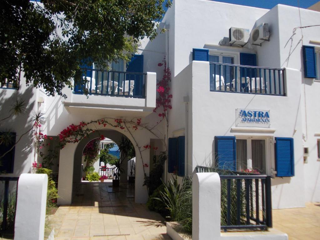 加藤-达拉特索Astra Hotel Apartments的白色的建筑,设有拱门和蓝色百叶窗