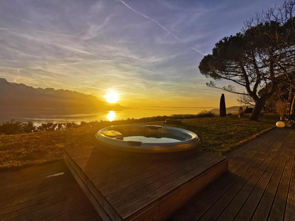 蒙特勒Sunset House with gorgeous view of the lake的浴缸位于木甲板上,享有日落美景