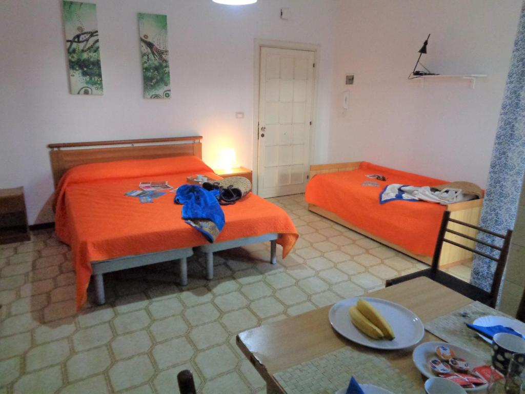 锡尔维玛丽娜MACRINUM Green Marine的配有橙色床单和桌子的客房内的两张床