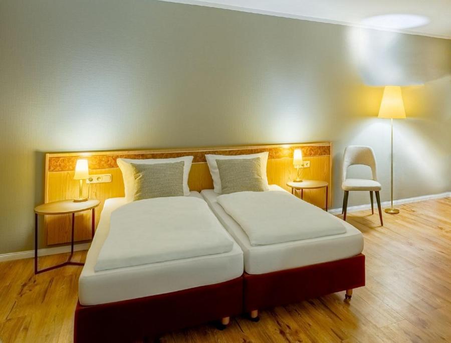 Grossbreitenbach康维格酒店的一间卧室配有两张床、两张桌子和椅子