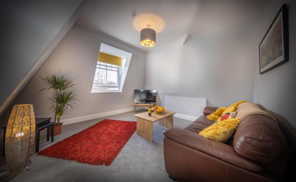 凯西克Loft Apartment, Keswick的客厅配有棕色沙发和红色地毯