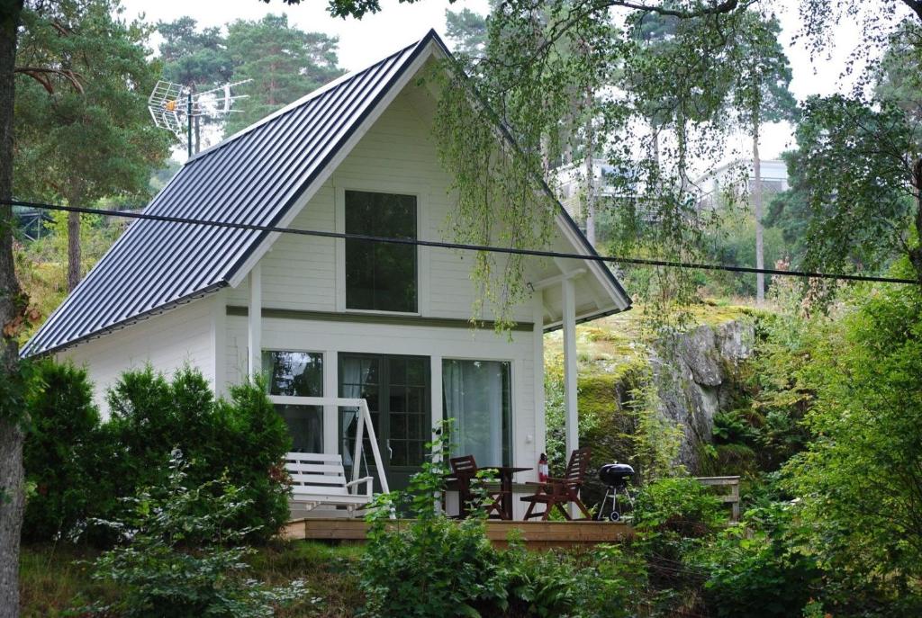 卢恩斯基尔Anfasteröd Gårdsvik - badstugor med loft的树林中带门廊的白色小房子