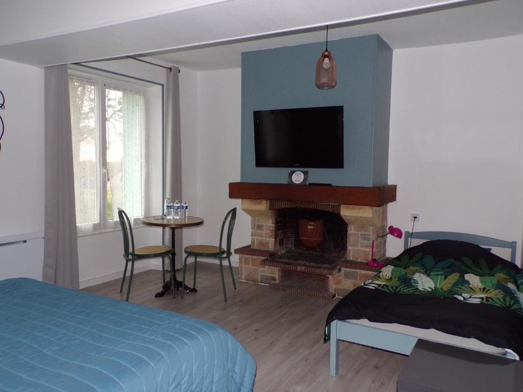 Méry-sur-CherA la Belle Etoile的一间卧室设有一张床和一个壁炉,配有电视