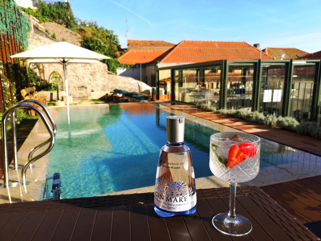 波尔图Porta Nobre - Exclusive Living Hotel的一瓶葡萄酒和一杯游泳池旁的玻璃