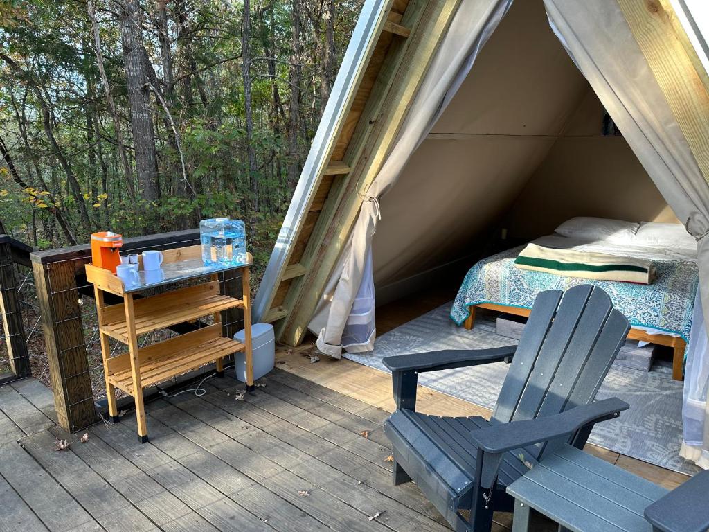 塔拉迪加Bohamia - Cozy A-Frame Glamp on 268 acre forest retreat的帐篷,配有一张床和一张椅子,位于甲板上