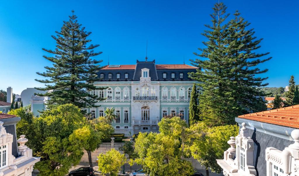 里斯本Pestana Palace Lisboa Hotel & National Monument - The Leading Hotels of the World的前面有树木的白色大建筑