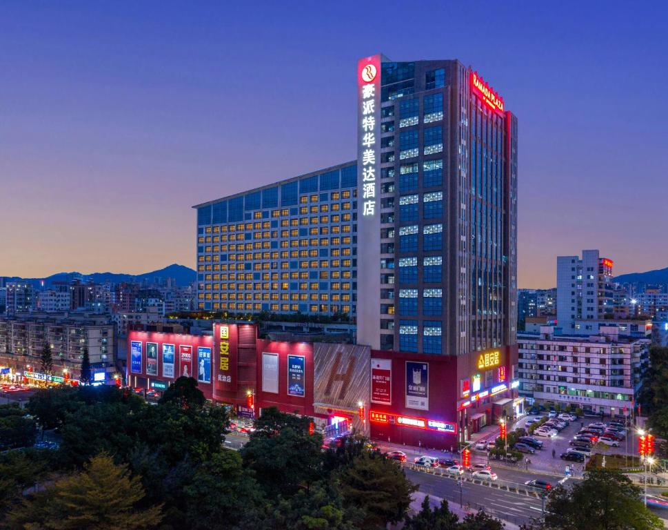 深圳深圳火车北站豪派特华美达广场酒店的一座高大的建筑,晚上在城市里点红灯