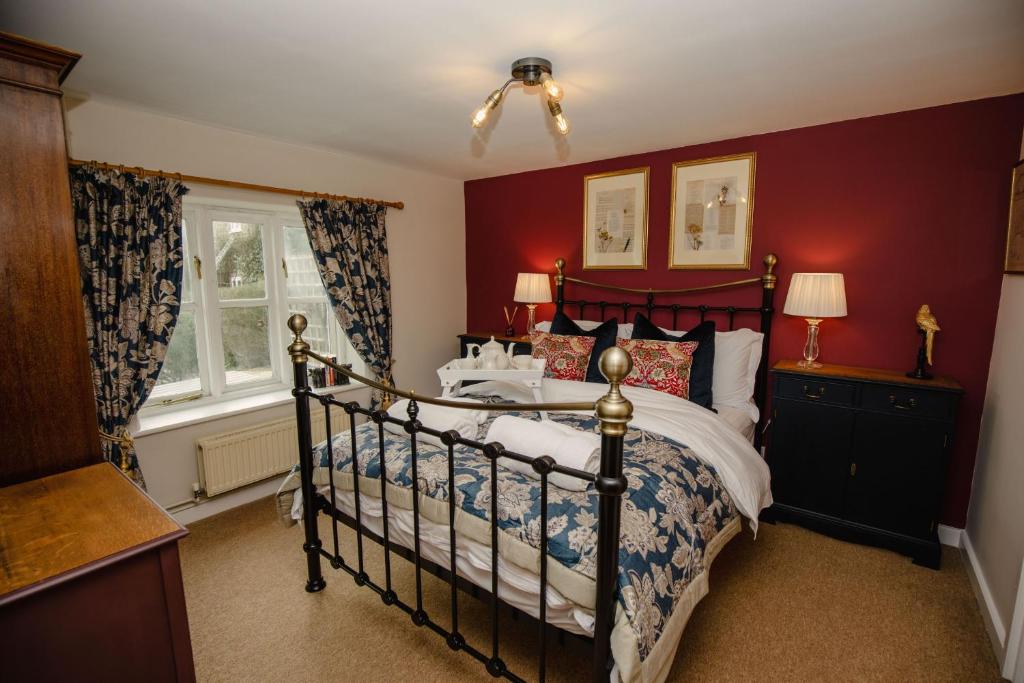 布里德波特Milkmaids Cottage - Rudge Farm Cottages的一间卧室设有一张床和红色的墙壁
