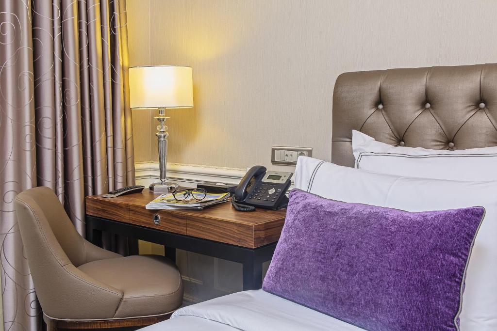 伊斯坦布尔梅洛迪巴格达缇里雅酒店的酒店客房配有一张床、一张书桌和一部电话