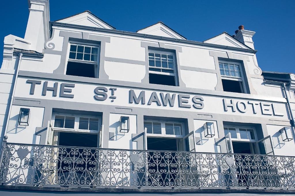 圣莫斯St Mawes Hotel的一座白色的建筑,上面写着一个有模特的旅馆