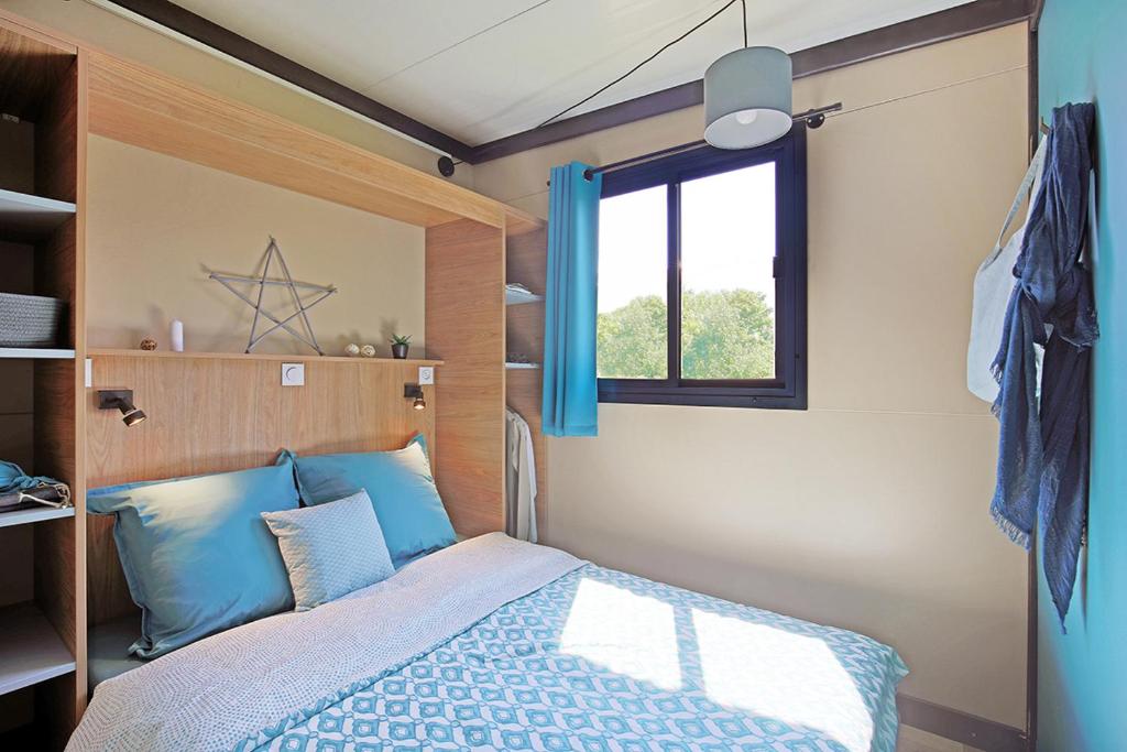 奥尔梅托RAS L'BOL的一间卧室配有一张带蓝色枕头的床和一扇窗户。