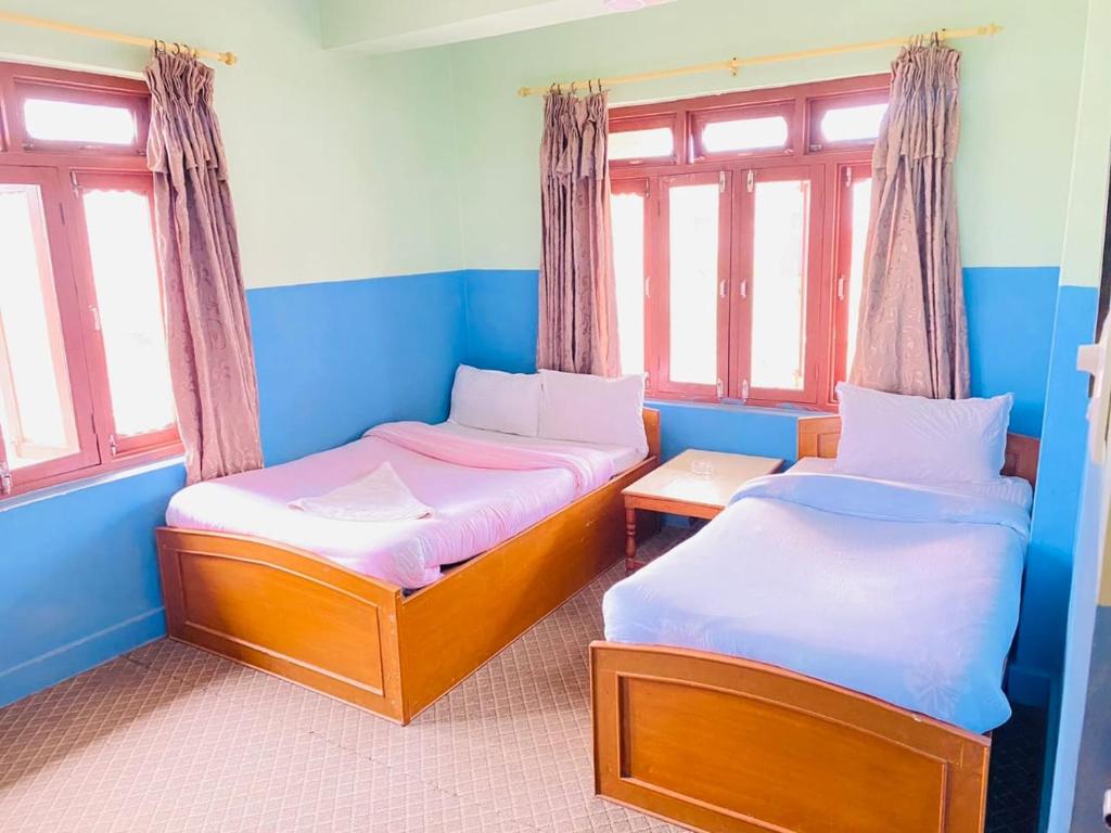 博卡拉HOTEL ICE VIEW POKHARA的配有两张床铺的蓝色墙壁和窗户