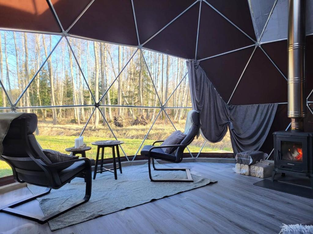Ozoli - Pirts / Viesunams的帐篷,配有两把椅子和壁炉