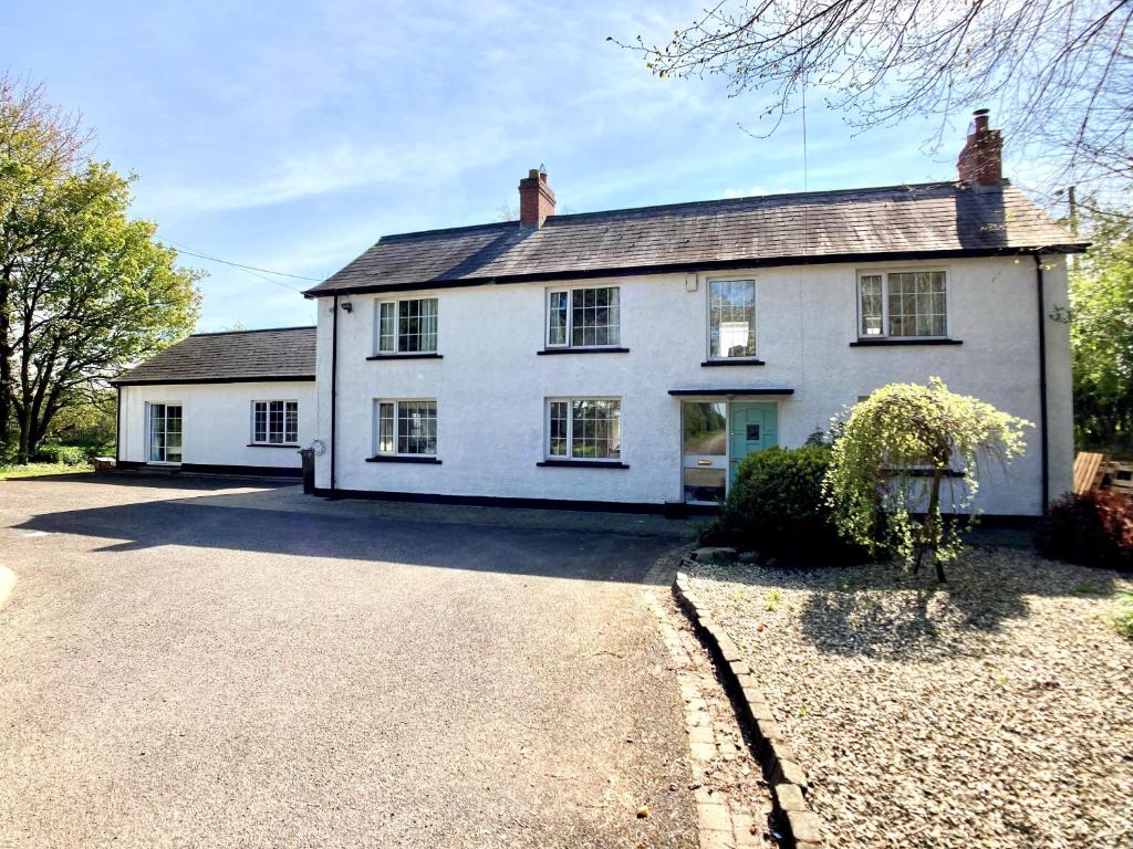 DoaghLarge Country Farmhouse with Garden and Stream的前面有车道的白色房子