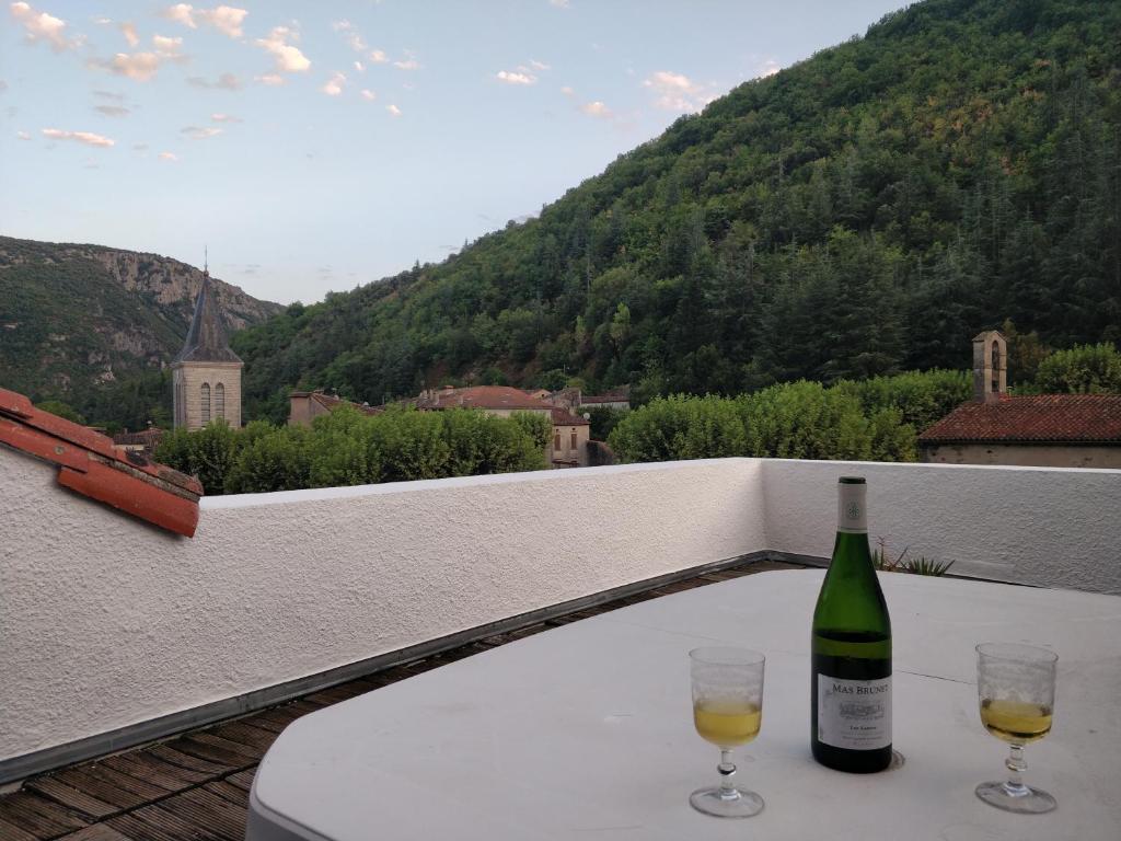 Saint-Laurent-le-MinierLovely Cevenol village house的一张桌子上放着一瓶葡萄酒,放上两杯