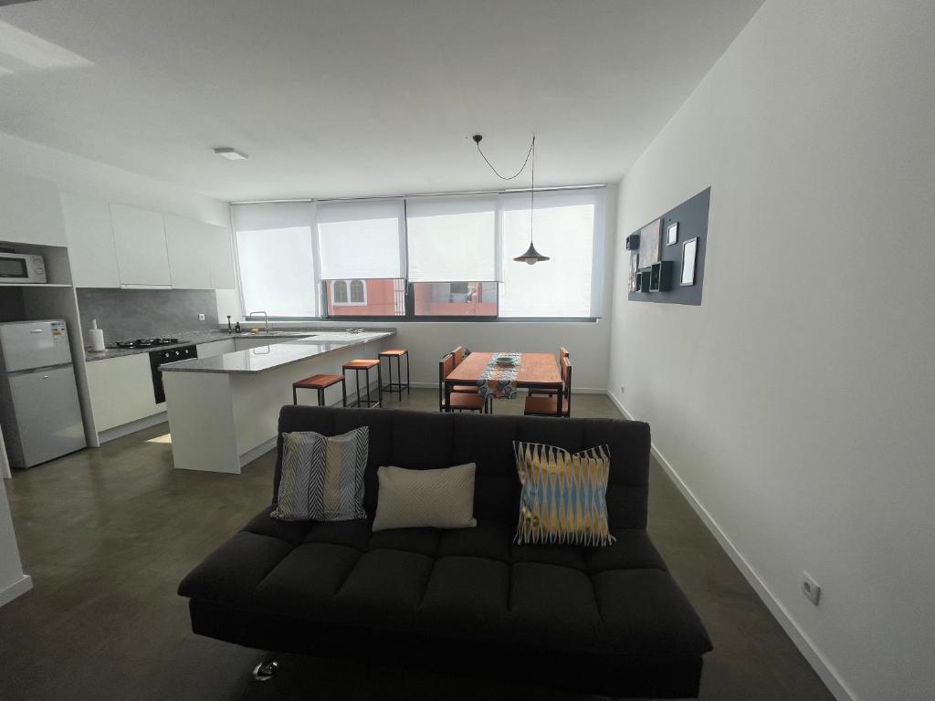 明德卢Tia Nita Apartamentos的一间带黑色沙发的客厅和一间厨房