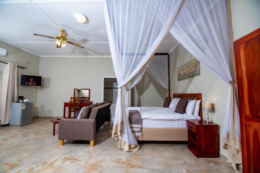 维多利亚瀑布Dzimbahwe Guest Lodge的一间卧室配有一张床、一张沙发和一个天花板